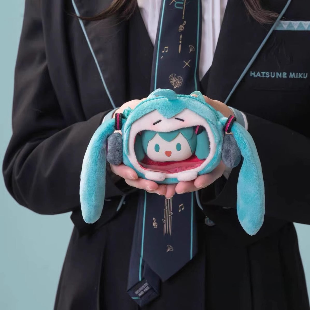 Hatsune Miku plush coin pouch held by person in Miku uniform, with mini doll inside.