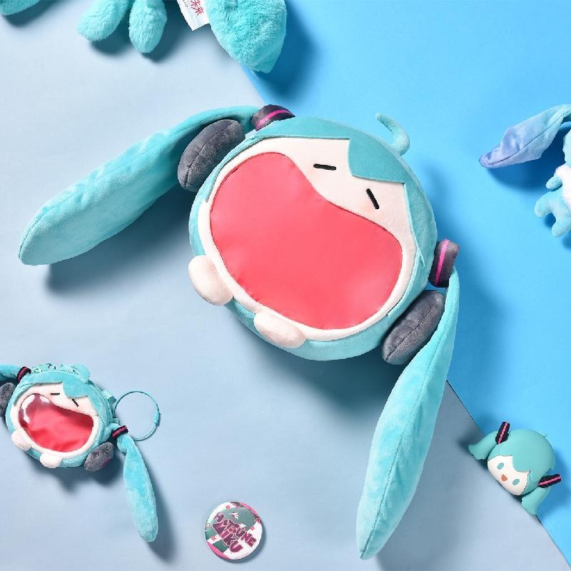 Hatsune Miku open-mouth plush bag with matching mini pouch and keychain on blue background.