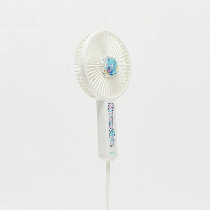 White handheld fan with Hatsune Miku design on the center and handle, hanging against a white background