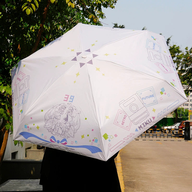Person holding compact Miku umbrella with retro-future design under sunny sky.