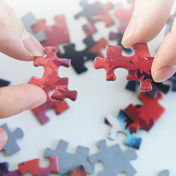 Close-up of two hands assembling red Hatsune Miku puzzle pieces