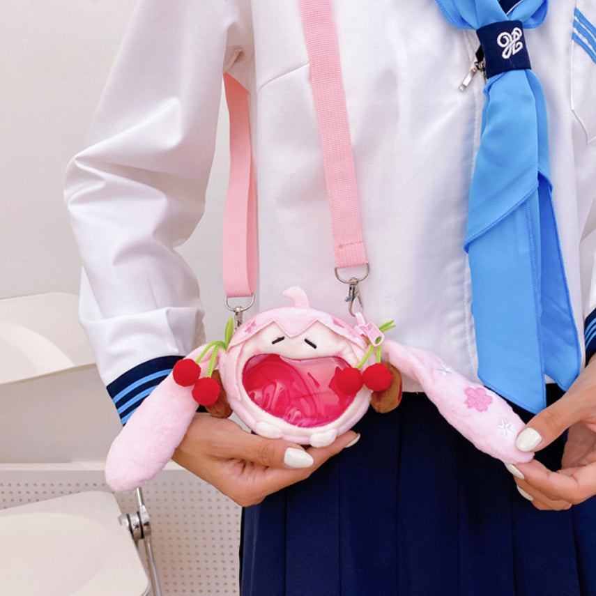 Sakura Miku plush crossbody bag with cherry details and clear pocket, held by model in uniform.