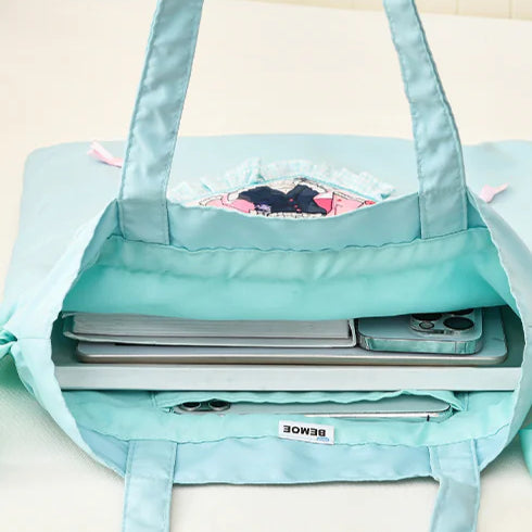 A light blue Miku tote bag holding a laptop, phone, and notebook, showing its spacious interior